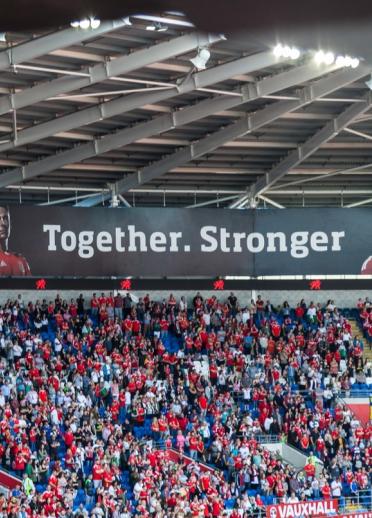 Wales football fans in the stands at Cardiff City Stadium with the 'Together. Stronger' banner .