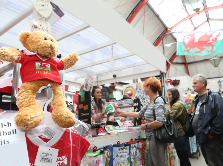 People buying things at a stall selling Wales merchandise.