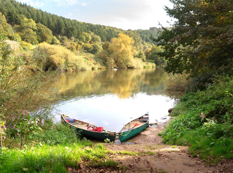 Two canoe's on the bank next to the River Wye.