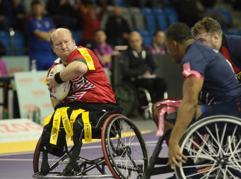 A man in a wheelchair with a rugby ball.