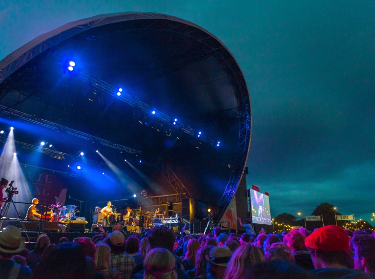 A crowd of people watching a band playing on a stage.