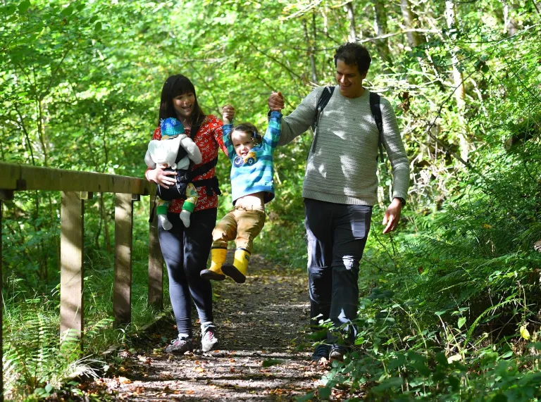 A family walking down a path in the forest.
