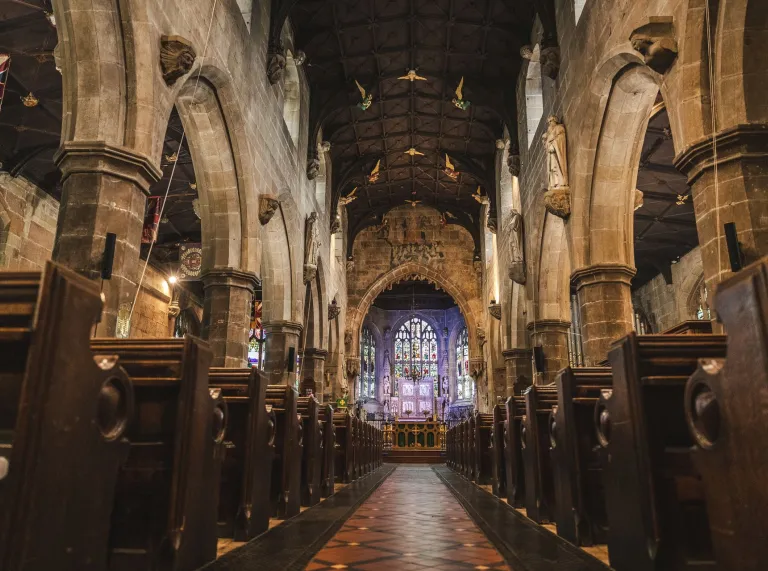 Interior view of a grand old Welsh church with large pillars and huge stained glass windows