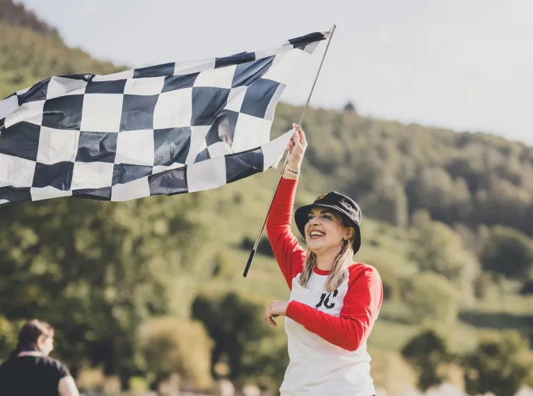 A woman holding a flag in the air ready to start a race