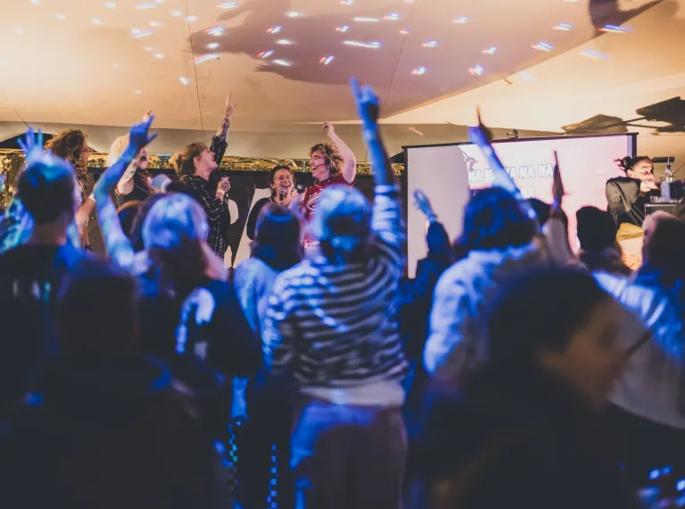 A group of women with their hands in the air on a dance floor