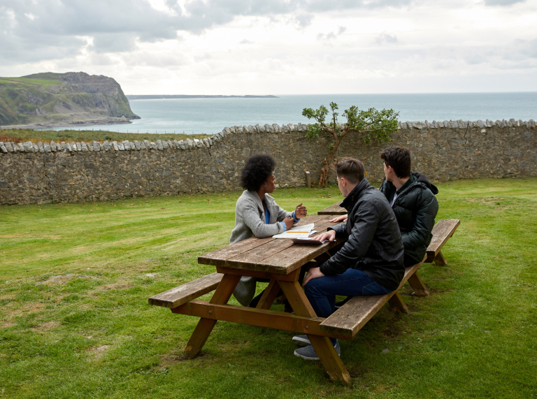 Welsh learners sat on bench looking out to sea, Nant Gwrtheyrn