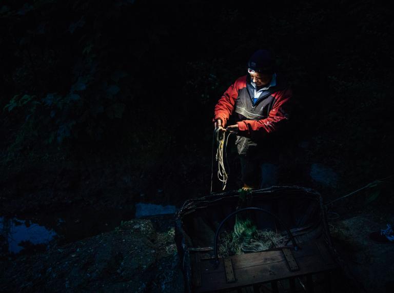Mann, der nachts im Korbboot fischt