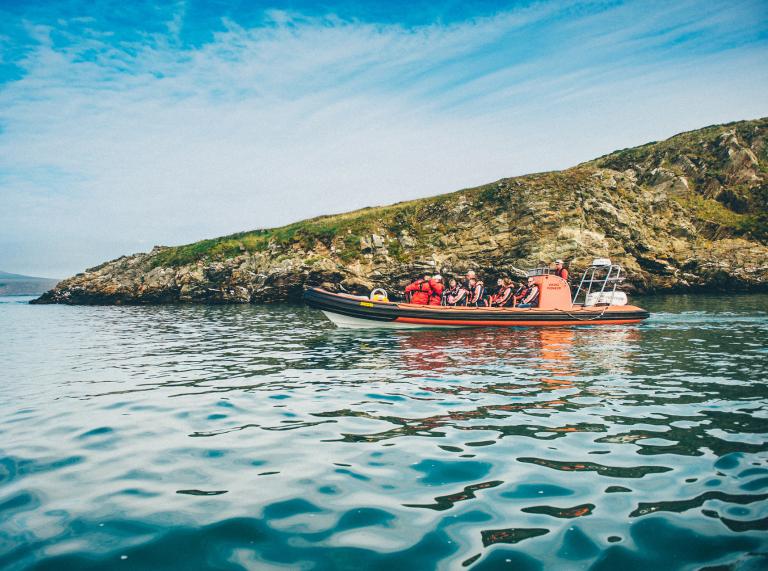 Das Boot des Menschen am Meer Delphin Schmierblutungen aus Ramsey Island, Pembrokeshire, Südwest-Wales