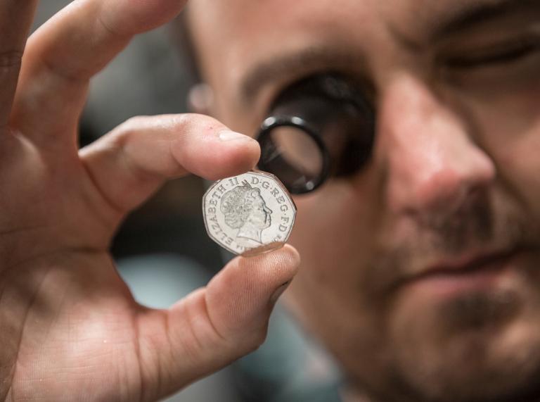 close inspection of a newly minted fifty pence coin at Royal Mint, Llantrisant