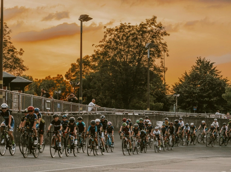 Radfahrer auf einer Radrennbahn im Freien mit Sonnenuntergang am Himmel