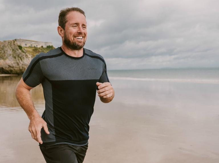 Shane Williams corriendo por la playa del norte de Tenby en entrenamiento para el triatlón Ironman Wales.