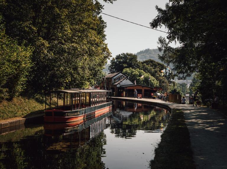 An image of a canal boat against a beautiful mountain backdrop