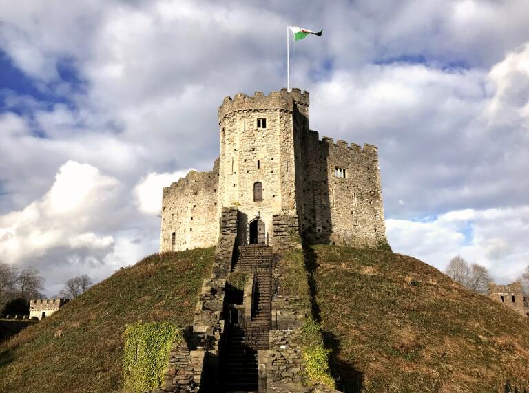 Norman Keep on top of a green grassy mound with the Welsh flag flying from the top