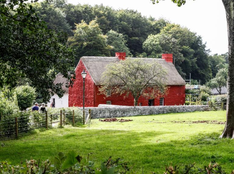 A view of a red cottage next to a green field.