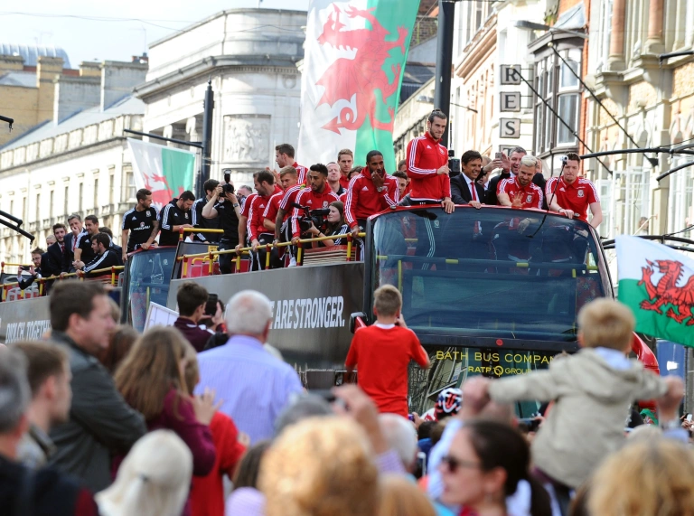 L'équipe de football du Pays de Galles sur le toit de leur bus touristique saluant la foule en dessous.