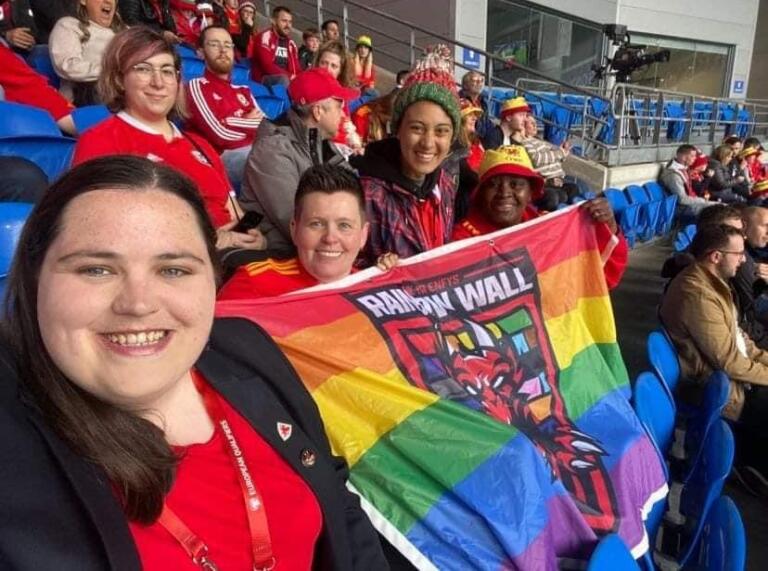 Image of Tracy Brown at a Wales match holding a rainbow flag