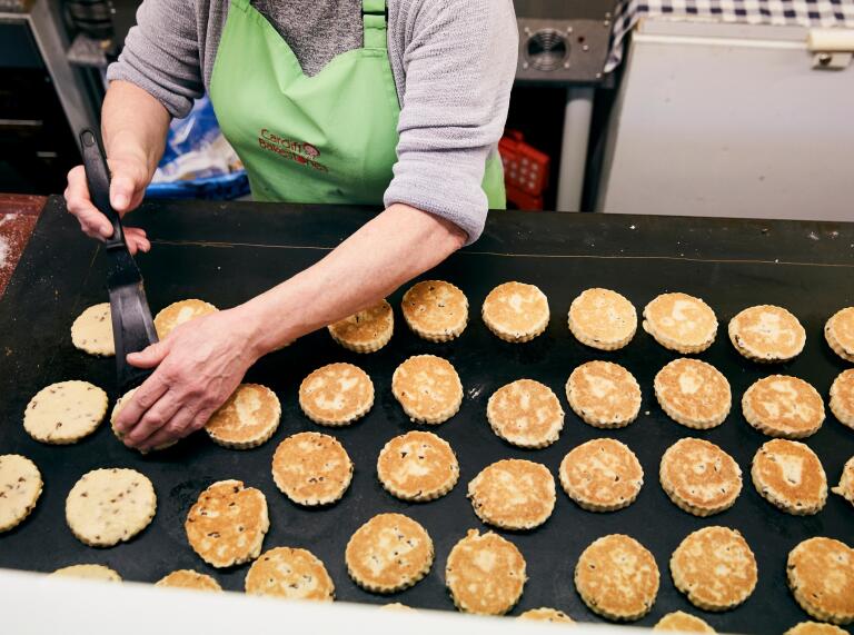 Welsh cakes being cooked on a large tray.