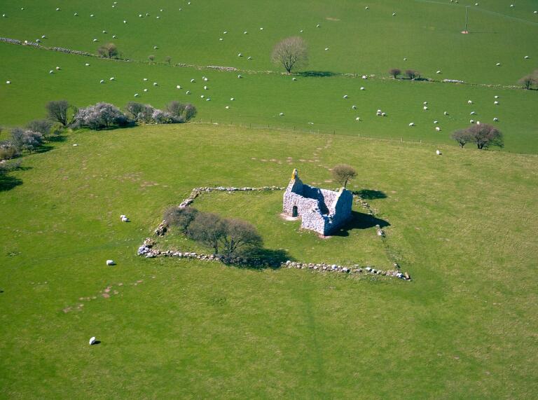 aerial view of old chapel surrounded by a field with sheep.