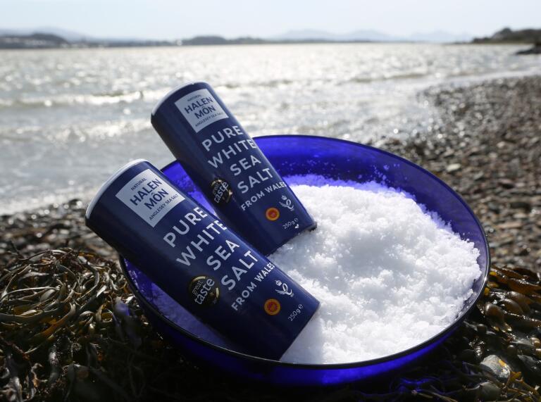 Two containers of Halen Môn sea salt sitting in a bowl of Halen Môn salt 