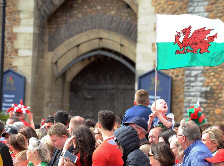 A child holding the Welsh flag above a crowd of people.