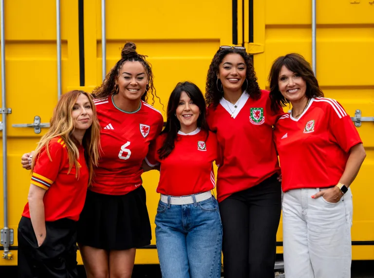 Eine Gruppe junger Menschen in Fußballshirts, die in die Kamera lachen