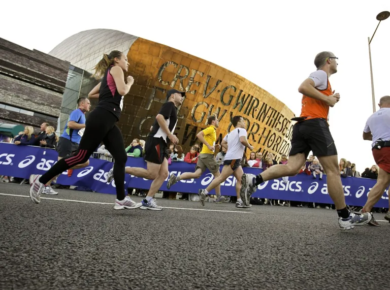 A group of marathon runners passing the Wales Millenium Centre in Cardiff
