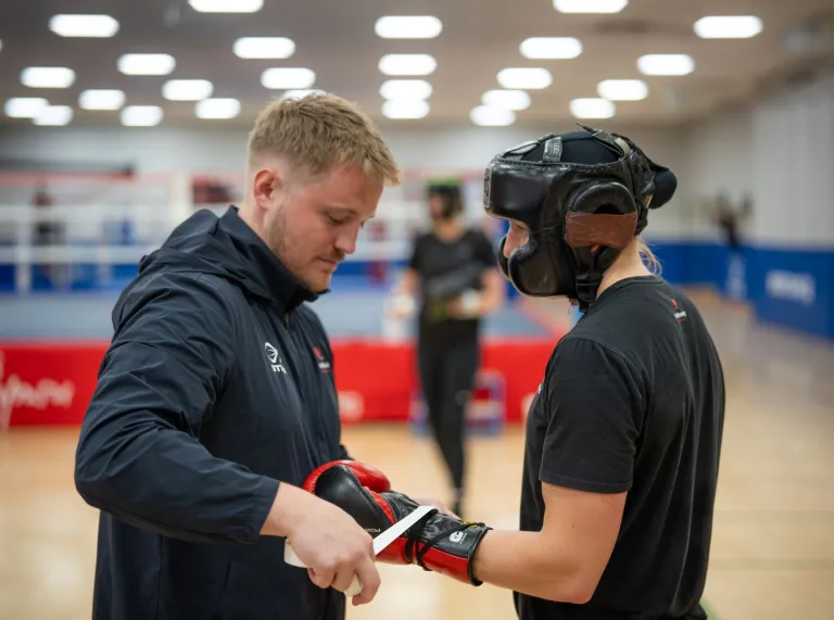 Rosie Eccles prepares for sparring as her coach tapes her boxing gloves in the gym.
