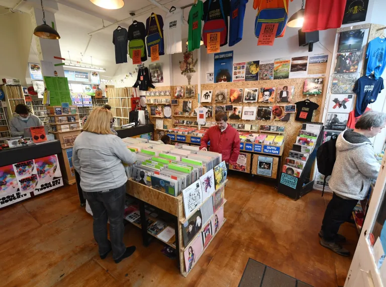Customers browsing vinyl records inside Spillers Records in Cardiff, with shelves of albums, music posters and T-shirts on display. 