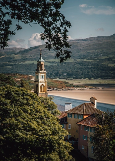 The top of buildings above the trees and next to the sea.