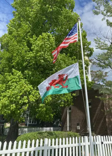 An American and a Welsh flag, attached to the same flagpole, flutter in the wind in Ohio, USA.