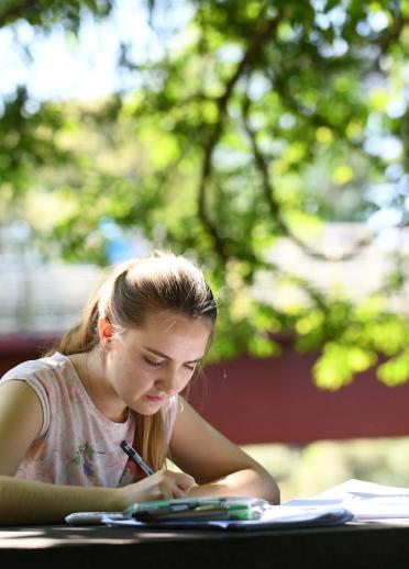 Chica estudiando en un banco en Bute Park, Cardiff