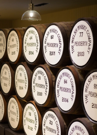 Barriles apilados de whisky Penderyn. Cada barril está marcado con la frase 'Penderyn. La compañía de whisky galés