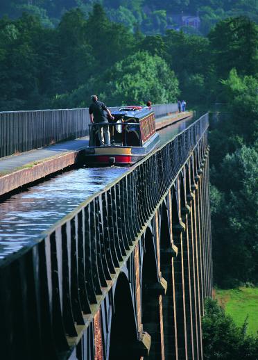 Man in a boat crossing a canal viaduct