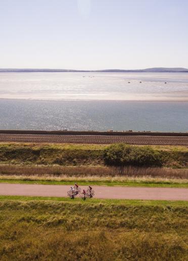 Radfahrer auf einem Weg, der parallel zum blauen Meer verläuft.