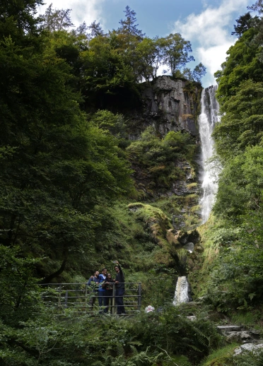 Personas sonriendo en un puente al pie de la impresionante cascada.