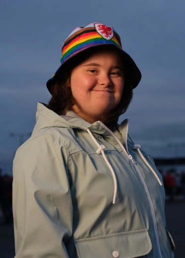Une personne souriant à la caméra portant un chapeau seau.