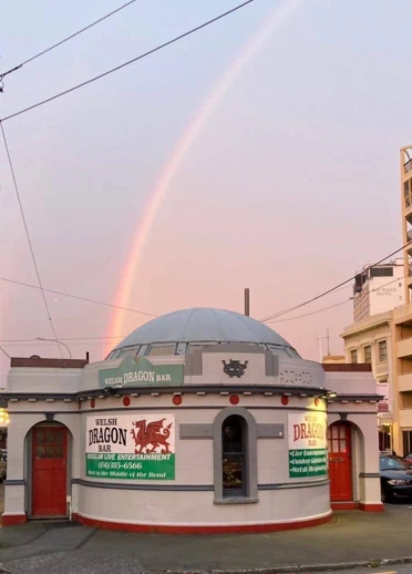 Exterior of the Welsh Dragon Bar in Wellington, New Zealand, with a rainbow overhead.