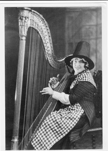 A woman wearing traditional Welsh dress sat playing a harp