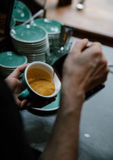 Pouring coffee into mug and saucer