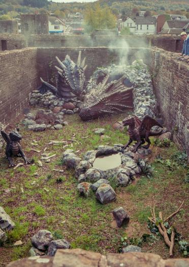 Vue plongeante dans le château avec des sculptures de dragon et en arrière-plan un homme regardant par-dessus le mur