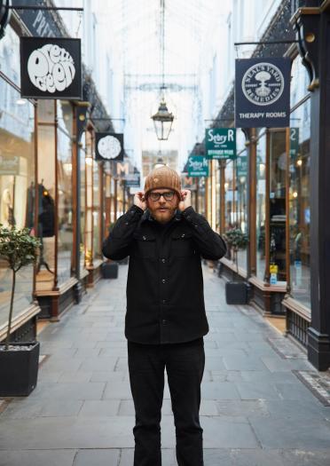 Huw Stephens holding beanie hat in Cardiff's Victorian Arcades