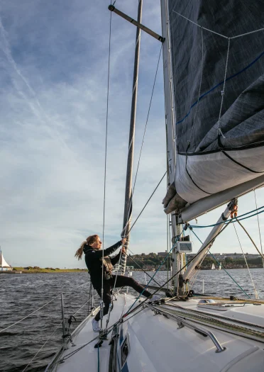 Hannah Mills, die auf ihrer Yacht in der Bucht von Cardiff im Alleingang die Segel einholt.