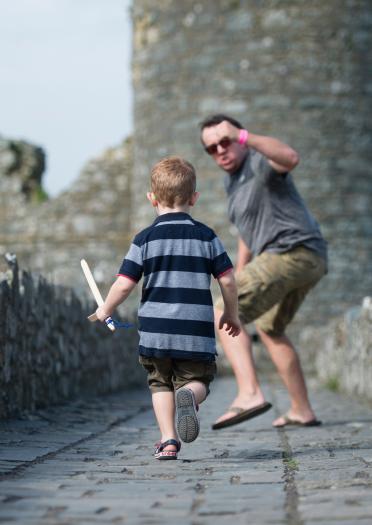 padre e hijo jugando en pared de castillo, Harlech Castle