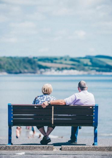 Back view of couple sat at Saundersfoot on bench looking out to the water