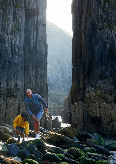 Père et fils explorant ensemble sur une plage rocheuse