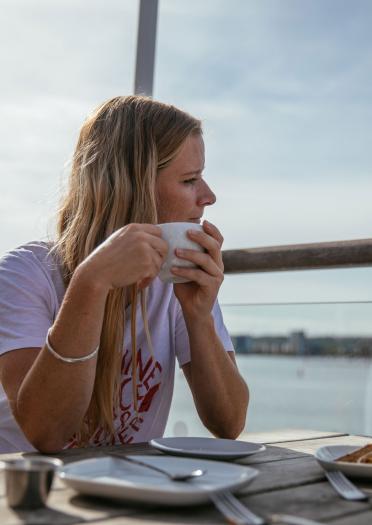 Hannah Mills bebiendo café mirando a la bahía de Cardiff