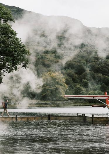 Luke Evans geht durch den Nebel zu einem kleinen Flugzeug am Ende eines Stegs.