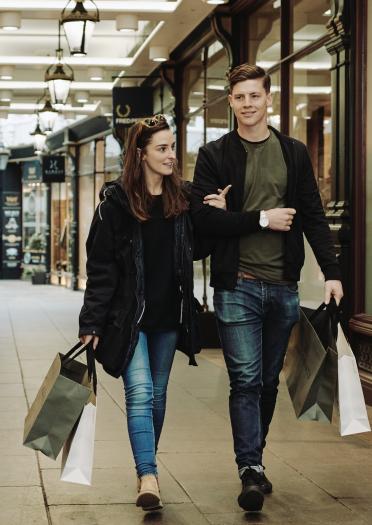 pareja llevando bolsas de compra en la galería comercial de Cardiff