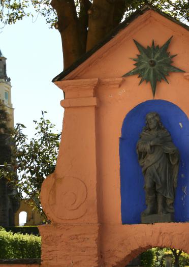 Terracotta building with statue in foreground and tower in background