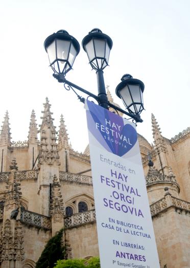 A Hay Festival banner hanging down a lamp post. A church building in the background.